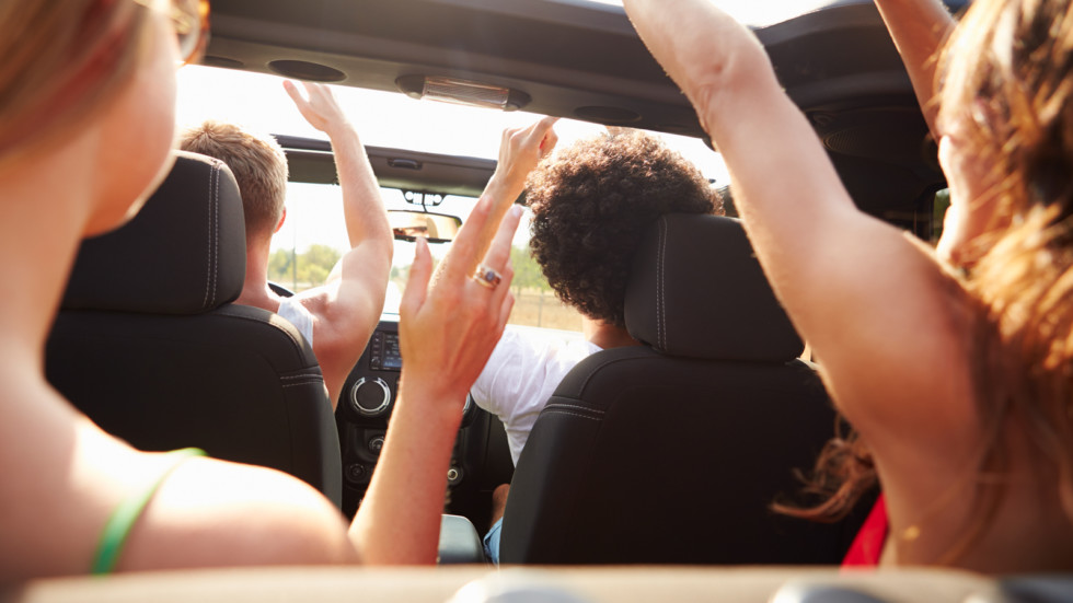 Group Of Young Friends Dancing In Back Of Open Top Car