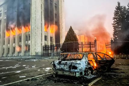 На фото: сгоревший автомобиль возле горящего здания акимата. Участники протеста против роста цен на топливо ворвались в здание акимата и пожодгли его.