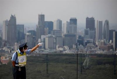 A security personnel wearing a protective face mask is seen with Tokyo's skyscrapers in the background amid the coronavirus disease (COVID-19) outbreak in Tokyo, Japan July 20, 2020. REUTERS/Issei Kato