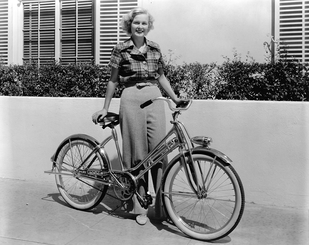 circa 1938: Gloria Stuart, the stage name of Gloria Stuart Finch ( 1909 - ) the American leading lady of the thirties is pictured with the bicycle that she regularly rides around the Century Fox studio between takes on her film. (Photo by Hulton Archive/Getty Images)