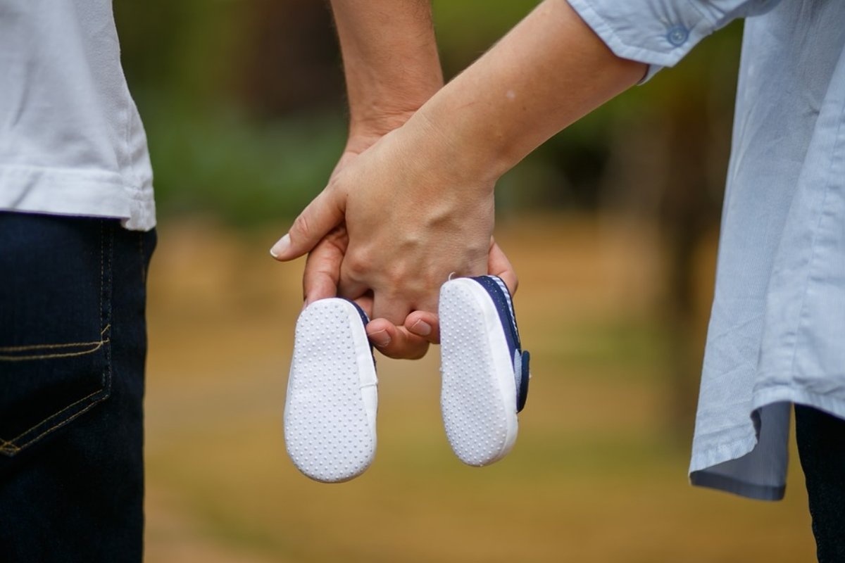 Мужчина и женщина держат в руках детскую обувь