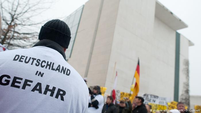 Участник акции в Берлине в футболке с надписью Германия в опасности