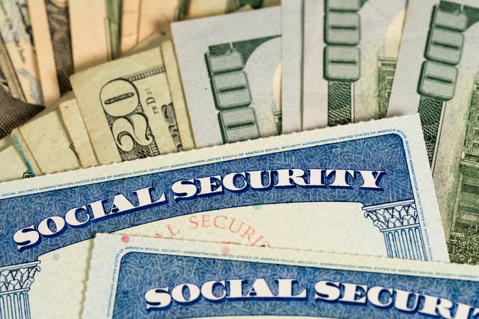Two Social Security cards on top of a pile of cash.