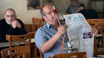 Посетитель кальянной в Дамаске читает газету