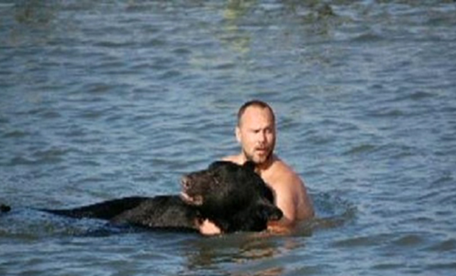 Черный медведь оказался в озере и не мог плыть. Ему на выручку пришел человек 
