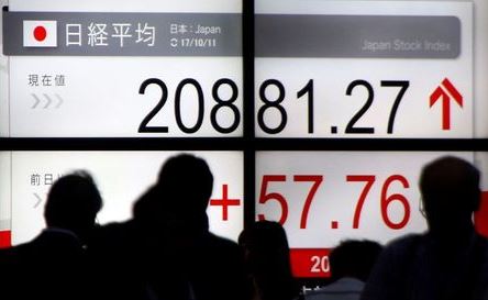 People walk past an electronic board showing Japan's Nikkei average outside a brokerage in Tokyo, Japan October 11, 2017. REUTERS/Toru Hanai