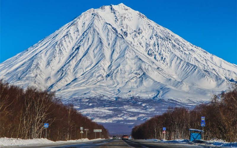 Камчатка. Дорога Петропавловск-Камчатский – Усть-Камчатск
Полуостров Камчатка – уникальная область на карте России. Это зона современного вулканизма, здесь находится 30 действующих вулканов и около 300 потухших. К сожалению, до большинства живописных мест на Камчатке добраться крайне сложно ввиду почти полного отсутствия автомобильных дорог. Главная камчатская трасса протяженностью 600 км от Петропавловска-Камчатского до Усть-Камчатска проходит рядом с Ключевской сопкой – самым высоким вулканом Евразии (4750 м). 