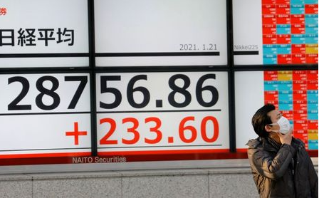 A man wearing a protective mask, amid the coronavirus disease (COVID-19) outbreak, stands in front of an electric board showing Nikkei index outside a brokerage in Tokyo, Japan January 21, 2021. REUTERS/Kim Kyung-Hoon