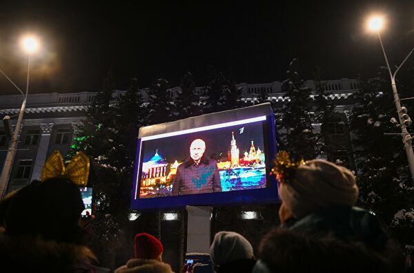 Люди смотрят трансляцию новогоднего обращения президента РФ Владимира Путина во время празднования Нового 2022 года в центре Кемерово