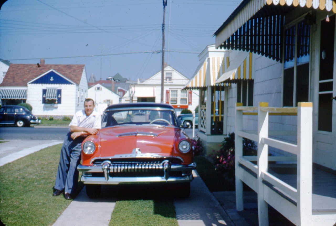 man-leaning-on-red-car