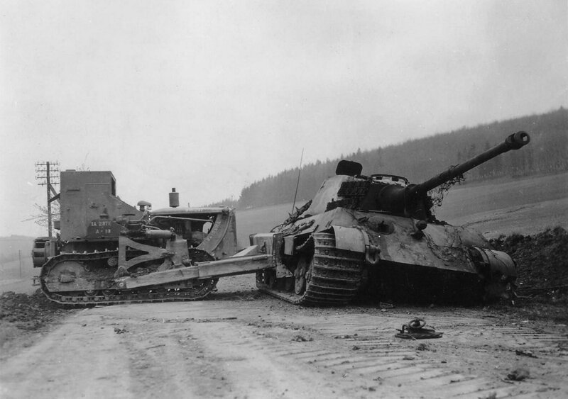Американский бульдозер D7 из 1-го инженерного батальона 1-й армии сталкивает уничтоженный немецкий тяжёлый танк "Королевский тигр" из 507 тяжёлого танкового полка на обочину. Окрестности Остероде, Германия, 12 апреля 1945 г. Великая Отечественная Война, архивные фотографии, вторая мировая война
