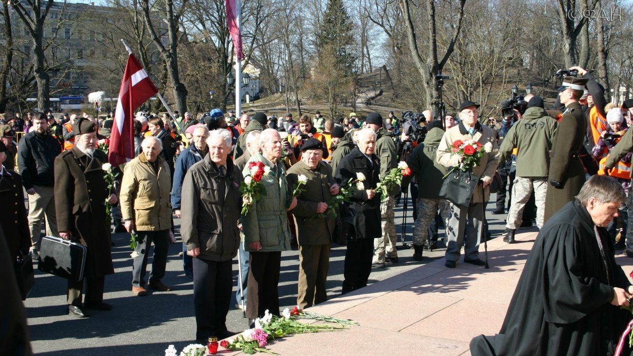 Шествие в память легионеров Waffen SS с редкими теперь ветеранами-эсэсовцами возглавляет, по традиции, лютеранский пастор. Склоненные государственные флаги, коленопреклоненный пастор – все чинно-благородно