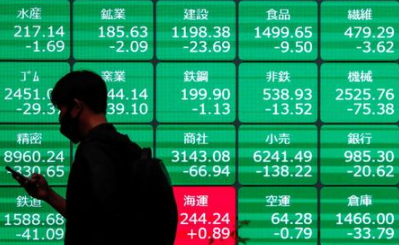 A man wearing a protective face mask walks past a stock quotation board outside a brokerage, amid the coronavirus disease (COVID-19) outbreak, in Tokyo, Japan May 11, 2021. REUTERS/Issei Kato