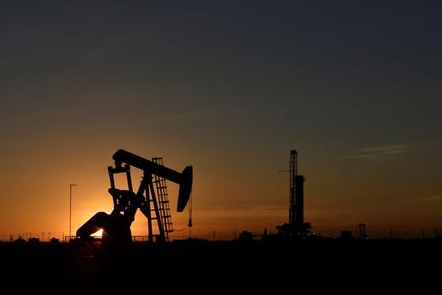 A pump jack operates in front of a drilling rig at sunset in an oil field in Midland, Texas U.S. August 22, 2018. Picture taken August 22, 2018. REUTERS/Nick Oxford