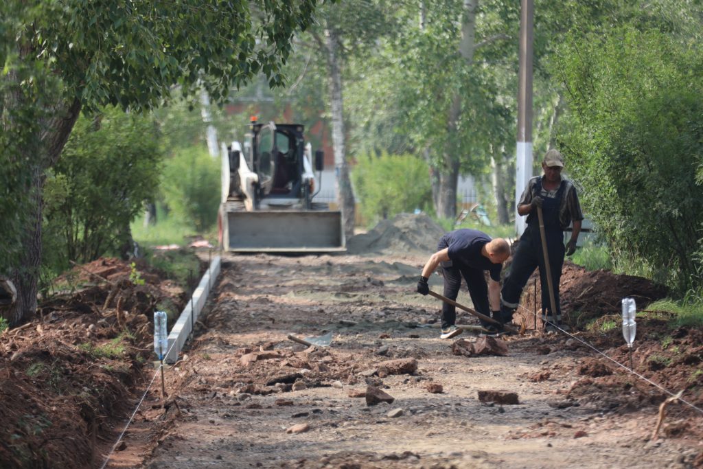 Рабочие строят дорогу в лесопарке