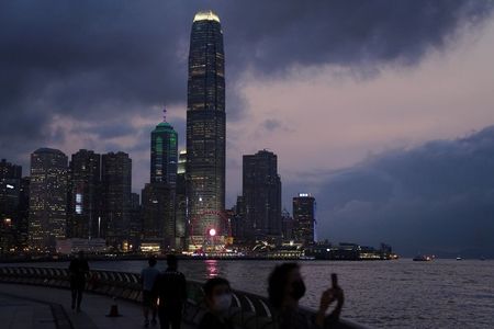 A woman takes pictures in front of high-rise buildings in the Central financial district after sunset in Hong Kong, China March 30, 2021. REUTERS/Lam Yik 