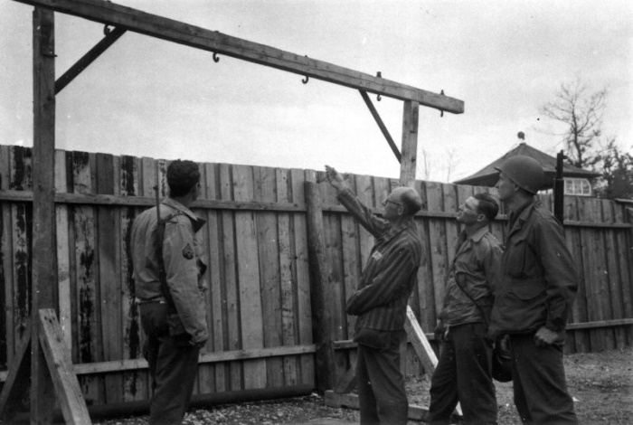 Бывший узник Бухенвальда показывает американским военнослужащим одну из виселиц, на которой казнили узников концлагеря, апрель 1945 года