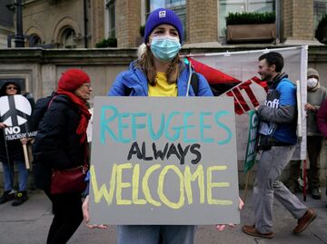 Девушка с плакатом Беженцам всегда рады на улице Лондона, Великобритания