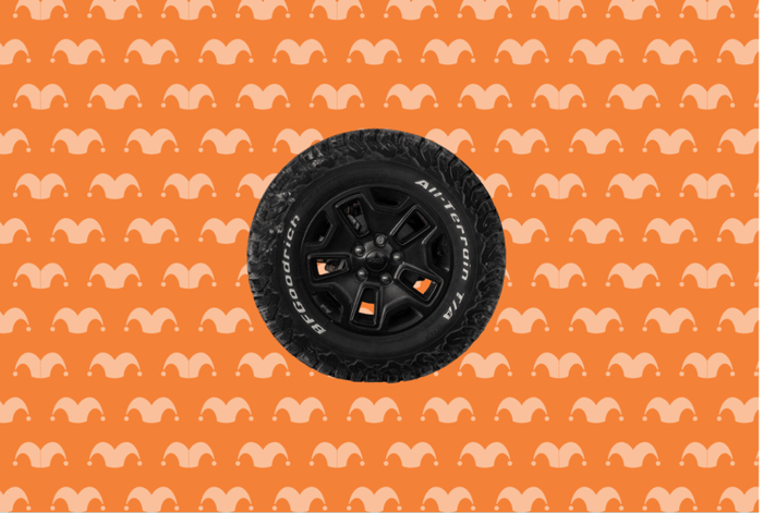 A car tire on top of an orange background covered in jester caps