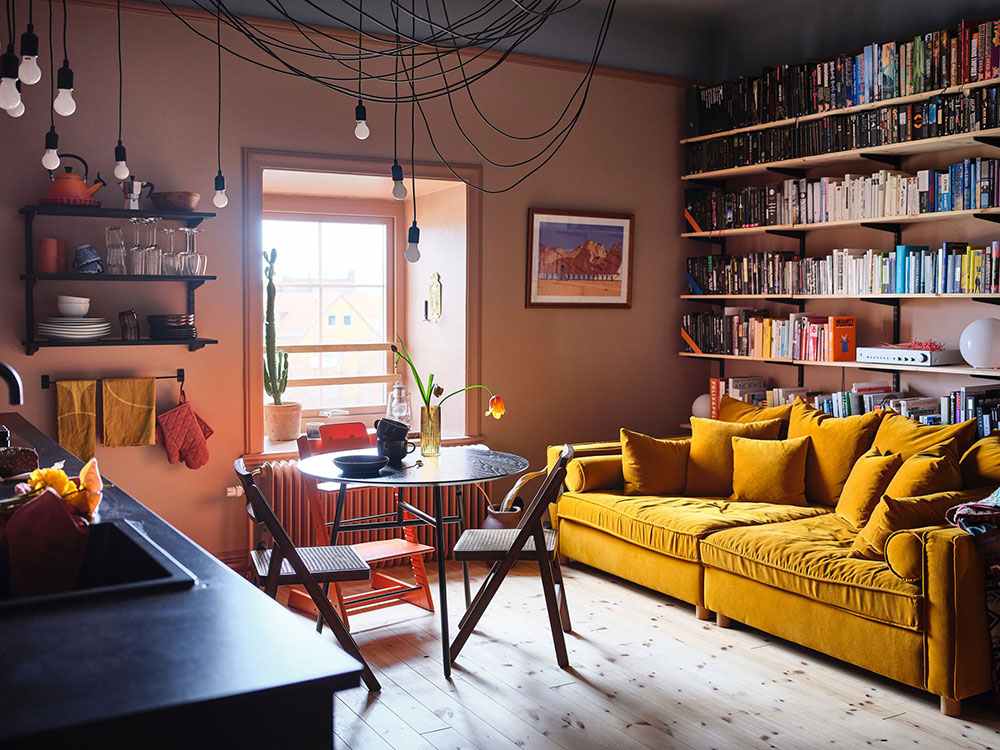 Маленькая квартира с пыльно-розовыми стенами и желтыми диваном 