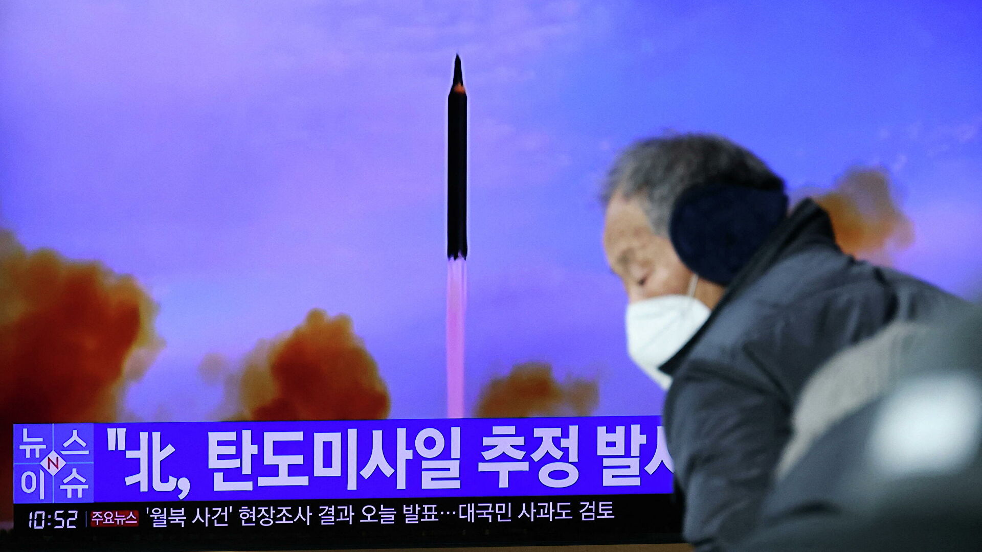 Мужчина проходит мимо экрана в Сеуле, транслирующего репортаж о запуске КНДР баллистической ракеты - РИА Новости, 1920, 30.01.2022