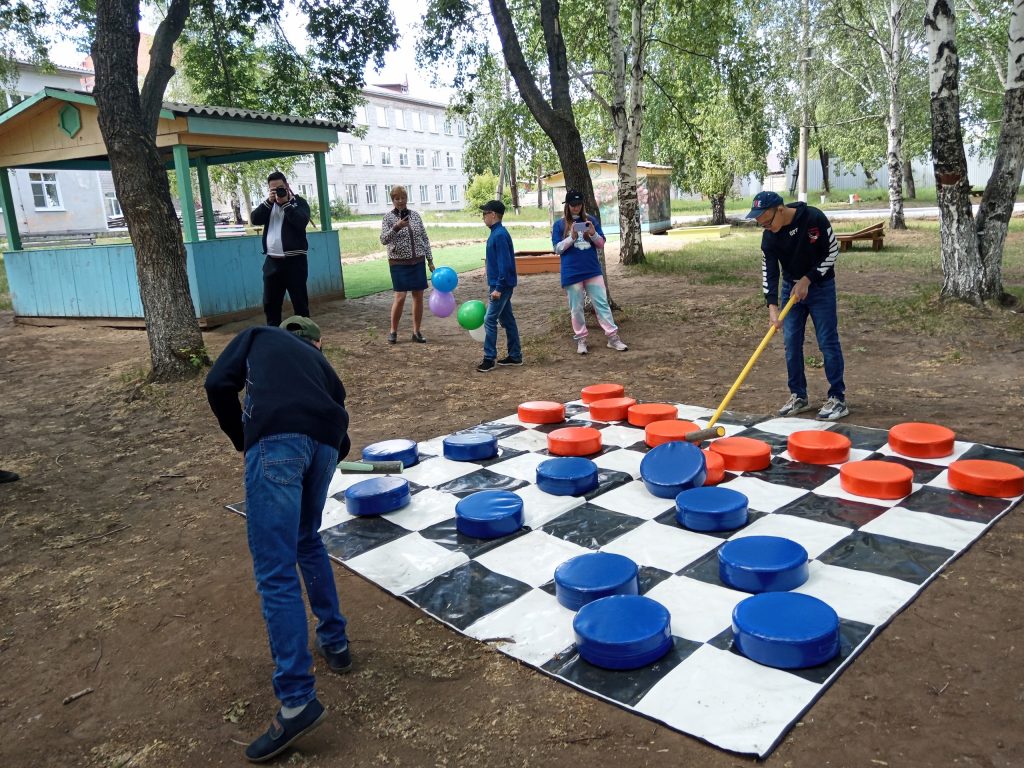 Люди играют в большие шашки на улице.