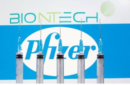 Syringes are seen in front of displayed Biontech and Pfizer logos in this illustration taken November 10, 2020. REUTERS/Dado Ruvic/File Photo