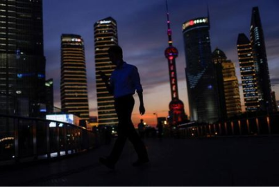 A man checks his phone while walking in Lujiazui financial district during sunset in Pudong, Shanghai, China July 13, 2021. Picture taken July 13, 2021. REUTERS/Aly Song