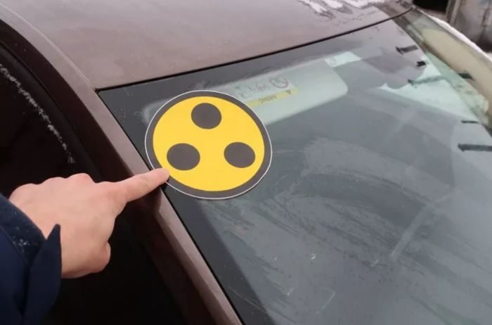 Что означает знак желтого круга с черными точками на стекле авто