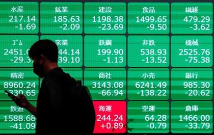 A man wearing a protective face mask walks past a stock quotation board outside a brokerage, amid the coronavirus disease (COVID-19) outbreak, in Tokyo, Japan. May 11, 2021. REUTERS/Issei Kato 