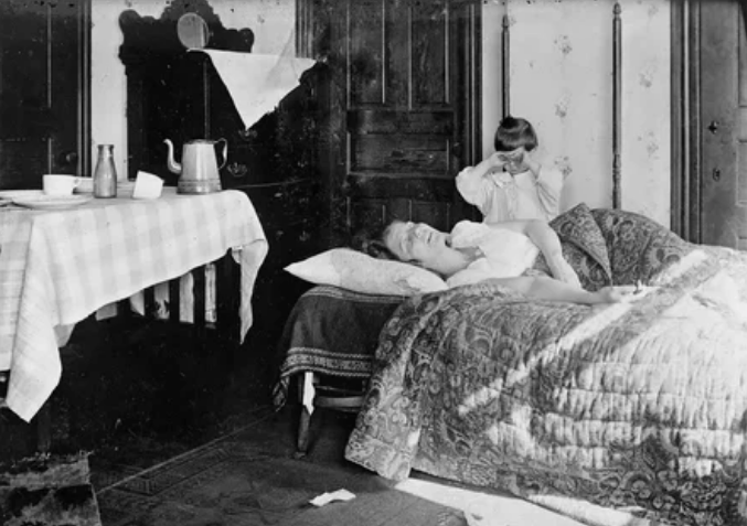 Девочка стоит рядом с сестрой, которая лежит в постели, ноябрь 1918 года