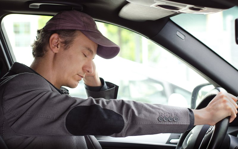 Bored, tired man sleeping at the wheel of his car