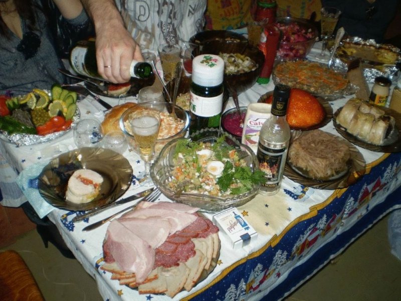  В реальности всё выглядело ближе к вот такому. Фото сделано уже в постсоветские годы, но само меню чисто советское — шампанское, водка, холодец, салат из свеклы (с чесноком и майонезом), оливье, крабовый салат с кукурузой, винегрет. СССР, новый год, праздник