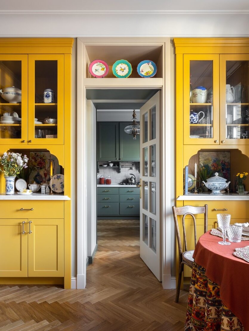 Основой композиции служат два желтых буфета, расположенные по обе стороны двери, ведущей в кухню. В них хранятся коллекции посуды, ваз и стекла.