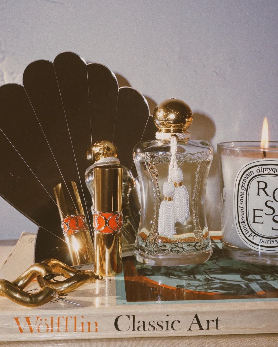 An aesthetic feminine tableau including Parfums de Marly, a YSL lipstick, and a seashell mirror from Urban Outfitters