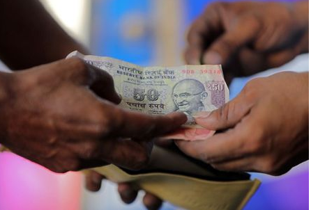 A customer hands a 50-Indian rupee note to an attendant at a fuel station in Ahmedabad, India, October 5, 2018. REUTERS/Amit Dave