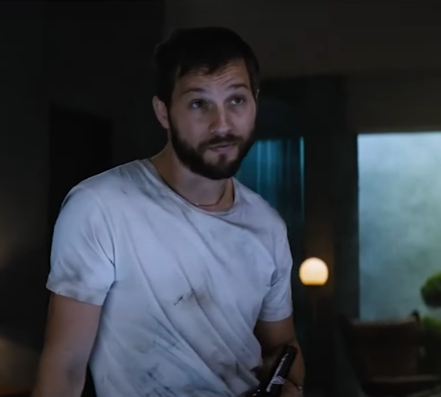 Logan Marshall-Green wears a white tee shirt and holds a beer