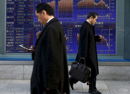 Men walk past an electronic board showing market indices outside a brokerage in Tokyo, Japan, March 2, 2016. Japan's Nikkei surged to a more than three-week high on Wednesday as the dollar rose against the yen after strong U.S. factory and construction data, giving exporters a boost and lifting the overall market. REUTERS/Thomas Peter