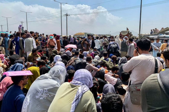 Афганцы собираются вдоль дороги, ожидая посадки в военный самолёт США, чтобы покинуть страну, в военном аэропорту в Кабуле, Афганистан, 20 августа 2021 г. 