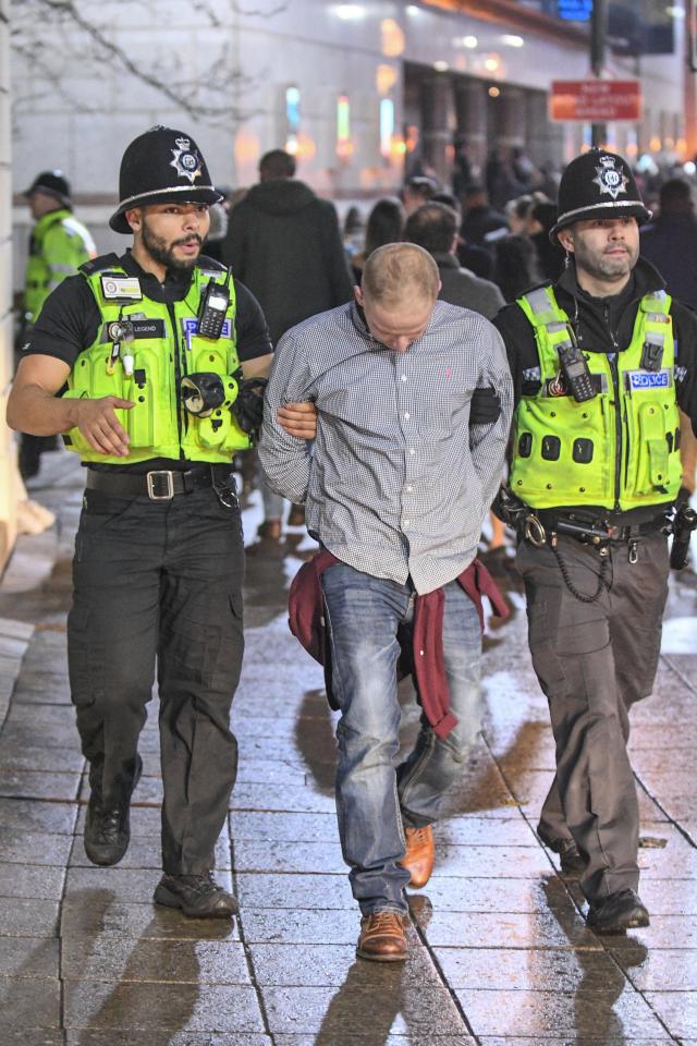 A man is led away from the party in Birmingham as he bows his head while being escorted by two officers
