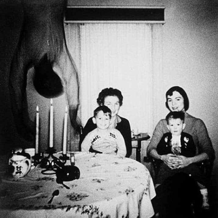 This family photo was said to have been taken in the 1950s. Two women sit by the dinner table, with candles cheerily lit and two happy boys on their laps. But when it was developed, or so the story goes, something else was revealed...a horrifying body hanging upside down, with a black void for a face, looming into the room.