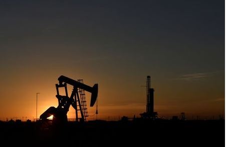A pump jack operates in front of a drilling rig at sunset in an oil field in Midland, Texas U.S. August 22, 2018. Picture taken August 22, 2018. REUTERS/Nick Oxford