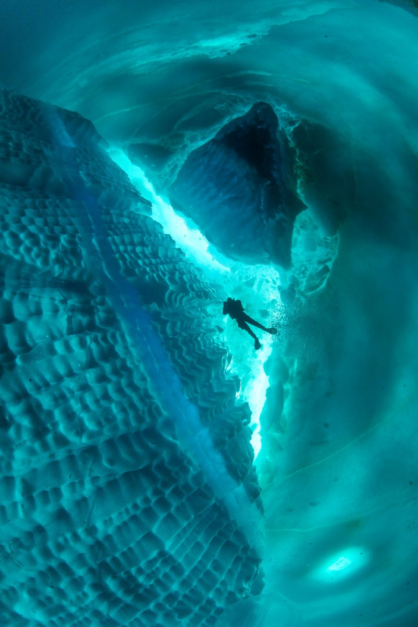 Stunning photos show ice dive beneath giant iceberg Stunning photos show ice dive beneath giant iceberg