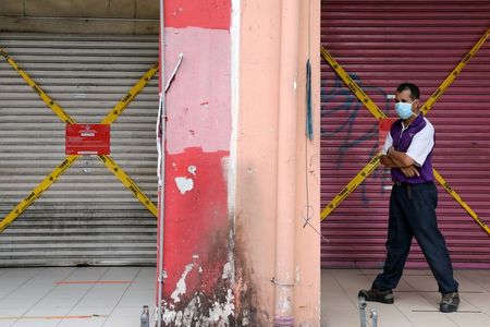 FILE PHOTO: A man wearing a protective mask walks past closed shops, amid the coronavirus disease (COVID-19) outbreak in Kuala Lumpur, Malaysia May 28, 2020. REUTERS/ Lim Huey Teng/File Photo