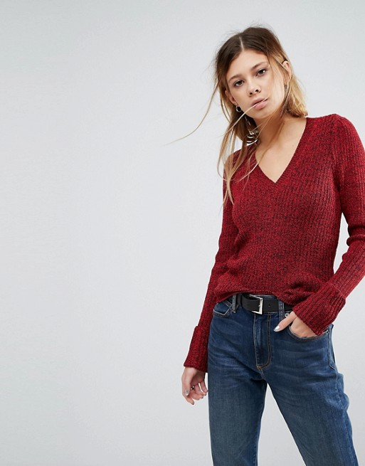 Модель в джинсах и бордовом свитере