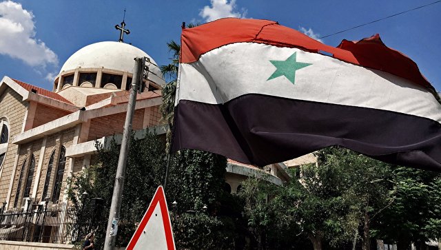 Государственный флаг Сирийской Арабской Республики у православной церкви в старом христианском квартале города Алеппо. Архивное фото