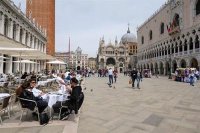 FILE PHOTO: People sit at outdoor tables at St. Mark's Square as Italy lifts quarantine restrictions for travellers arriving from European Union countries, Britain and Israel and begins offering COVID-free flights in a bid to revive the tourism industry, in Venice, Italy, May 16, 2021. REUTERS/Manuel Silvestri//File Photo
