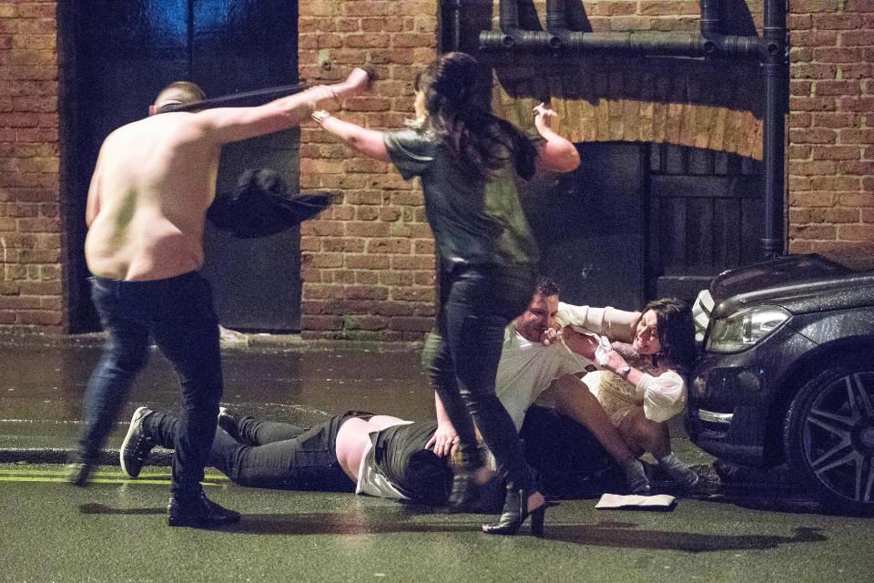 A shirtless man and a woman clash as another man lies in the gutter in Manchester city centre