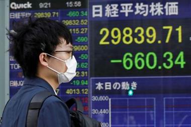 A man wearing a protective mask, amid the COVID-19 outbreak, walks past an electronic board displaying Japan's Nikkei index outside a brokerage in Tokyo, Japan, September 21, 2021. REUTERS/Kim Kyung-Hoon 