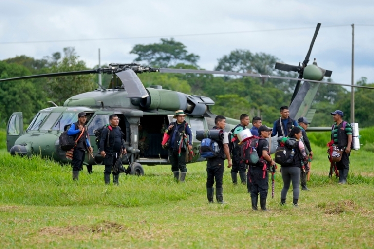 На фото: мужчины из числа коренных народов ждут посадки на вертолет на военной базе в Каламаре, Колумбия, вторник, 23 мая 2023 года, чтобы помочь в поисках четырех детей из числа коренных народов, пропавших без вести после авиакатастрофы со смертельным исходом. Колумбийские войска обнаружили обломки самолета 16 мая вместе с телами пилота, гида и матери детей, но детей не было видно.